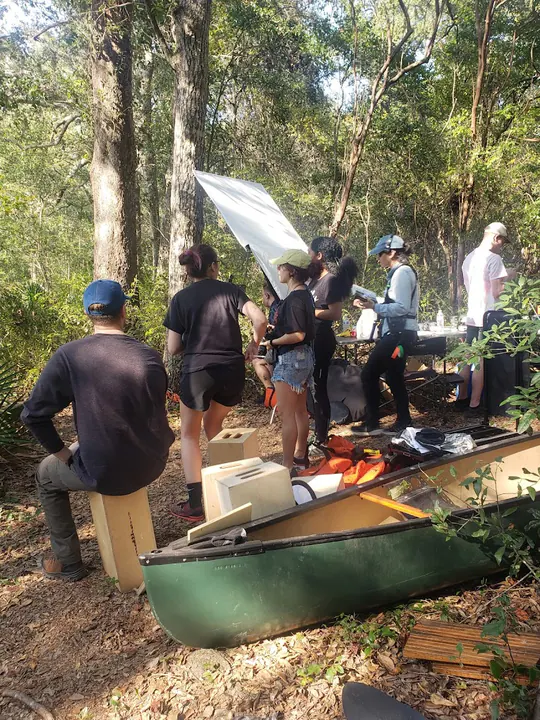 Crew with a green canoe in the woods