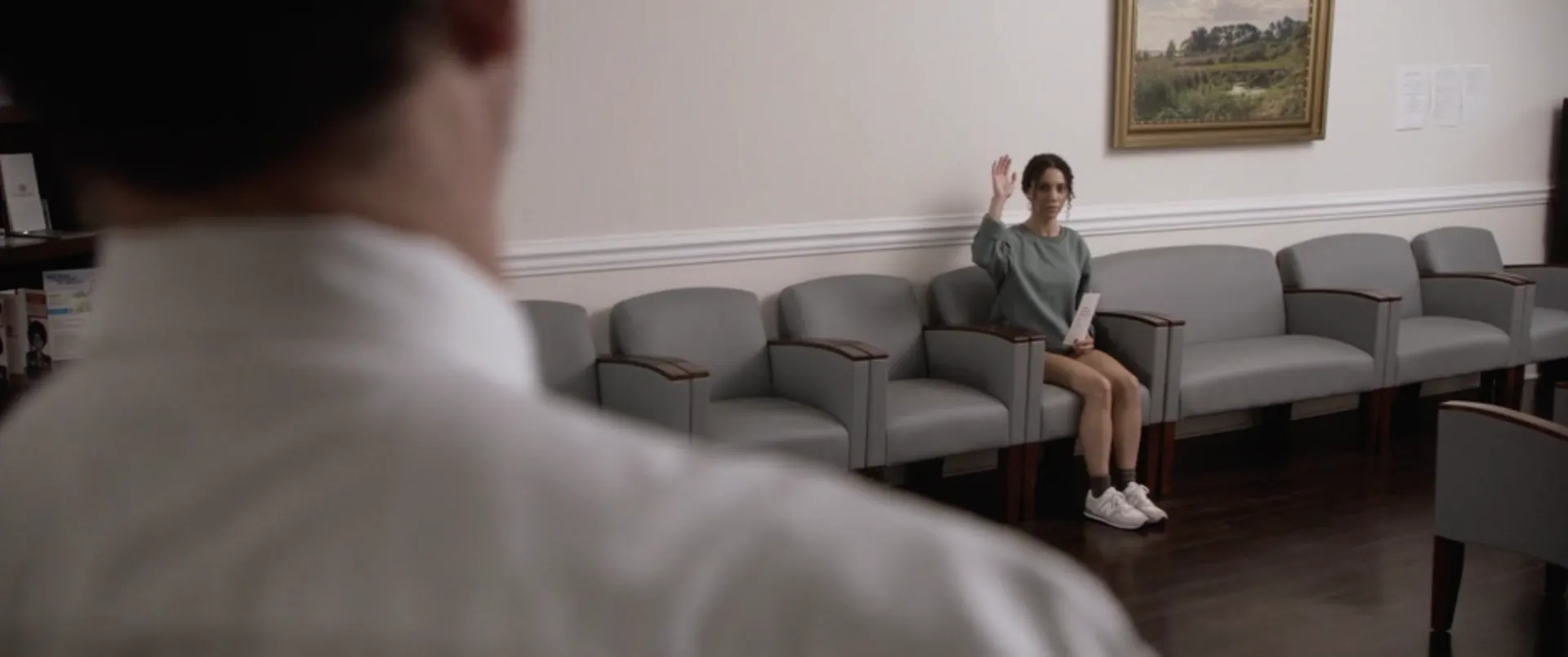 A woman waves from a clinic waiting room