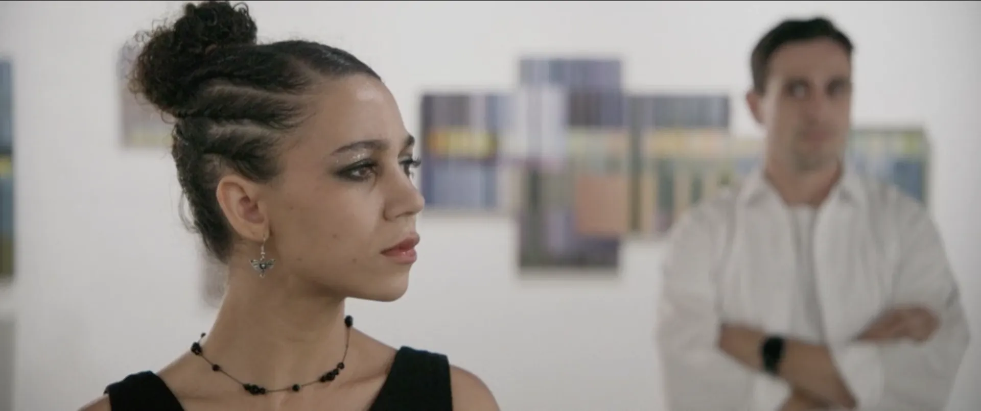 A woman in a gallery, a man behind her