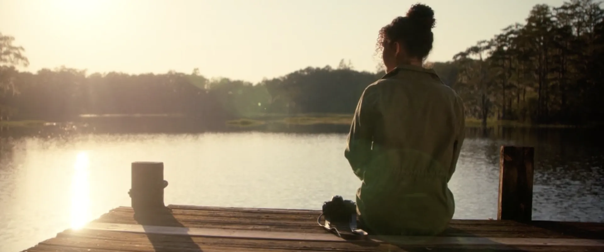 A woman sitting on a dock by a lake